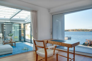 A luxury beach house with glass windows and the beautiful scenery of the sea in the background