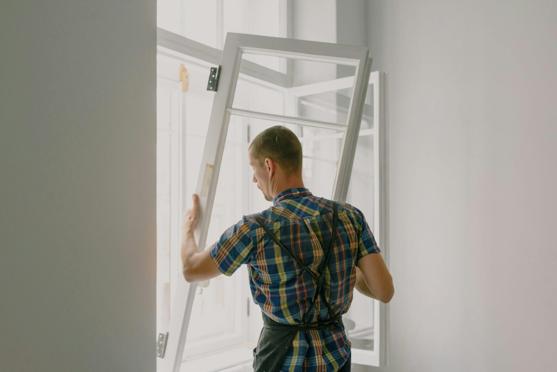 Un instalador profesional que instala una ventana moderna en el interior de una casa bien iluminada.