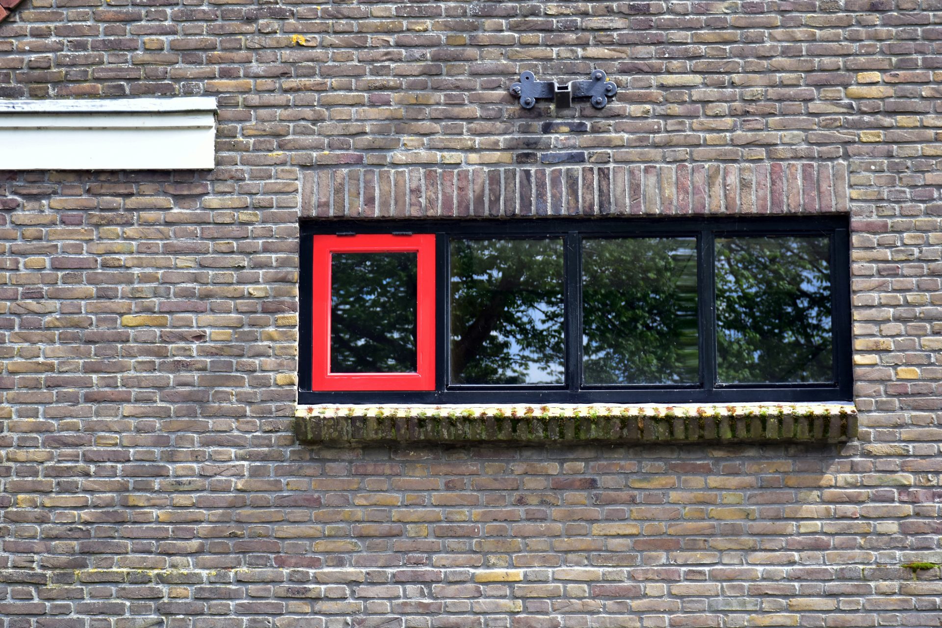 Un edificio de ladrillo con una ventana roja y un alféizar blanco.
