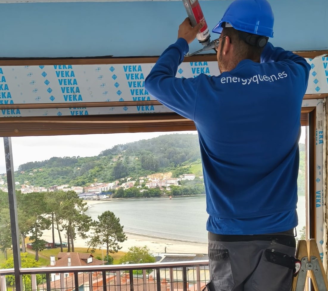 Vista posterior de un trabajador irreconocible en un delantal montando una ventana cerca de una máquina perforadora y puertas en un piso
